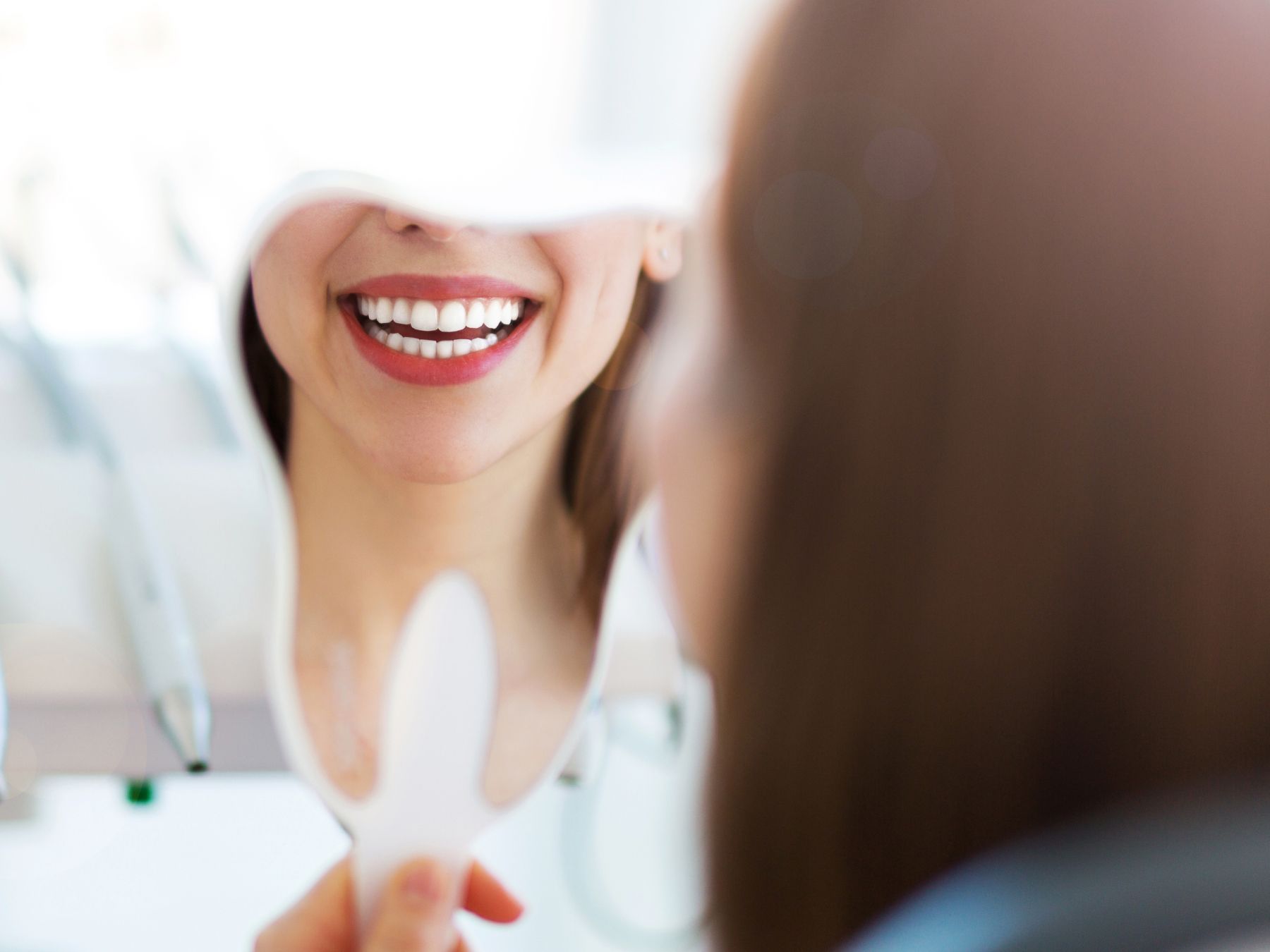 dentist patient model smiling into a tooth shaped mirror