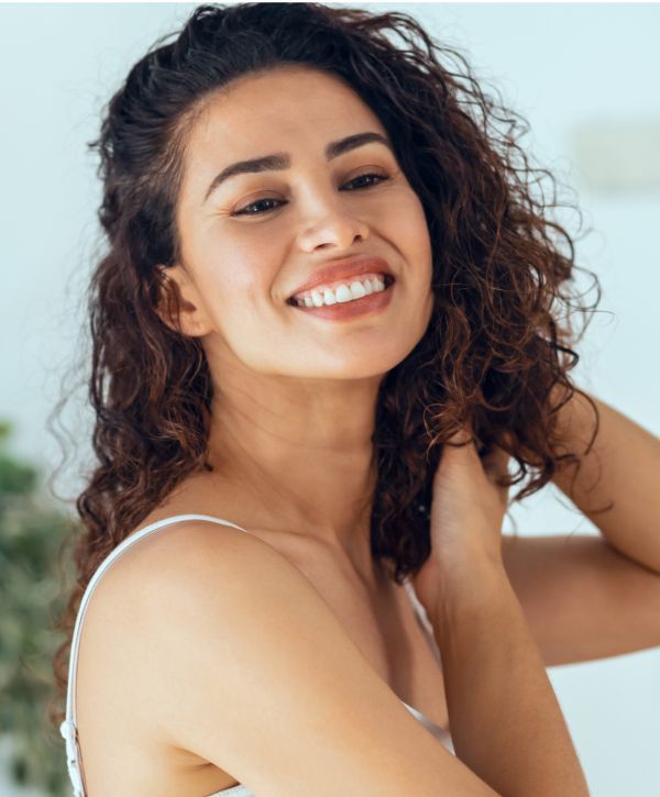 composite dental filling patient model touching her curly hair and smiling