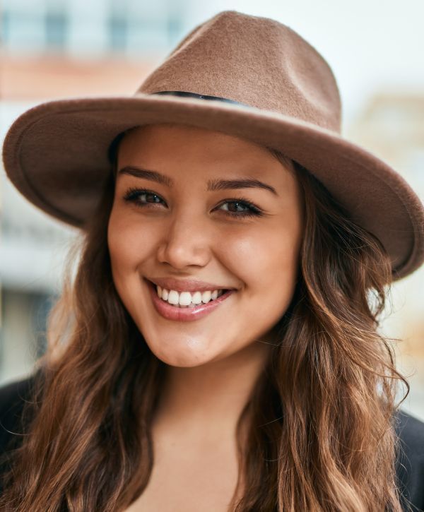 dental crown patient model smiling in a wide-brimmed sun hat