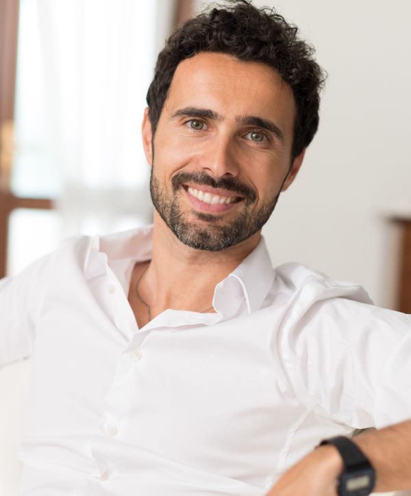 tooth extraction patient model smiling in a white button-up shirt