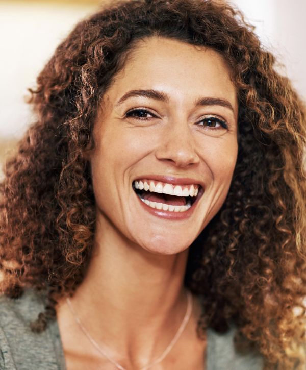 dental veneer patient model with curly hair smiling broadly